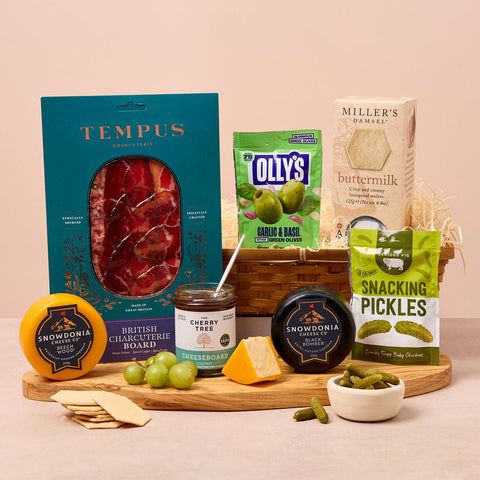 Assorted food products including a box of Tempus, Olly's pickles, and Snowdonia cheese on a wooden board.